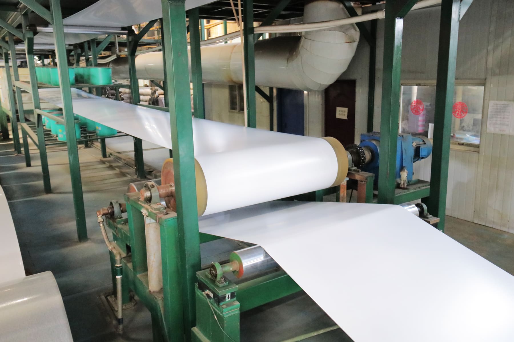 White coated sheet moving through production equipment